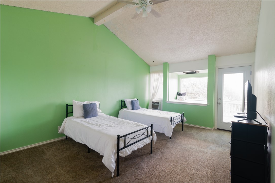 Photo #16 The second bedroom is located on the third floor with a high vaulted ceiling and carpet flooring.