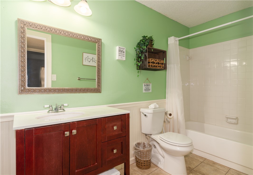 Photo #18 The main bathroom features a modern vanity, a decorative mirror, and a tub/shower combo.