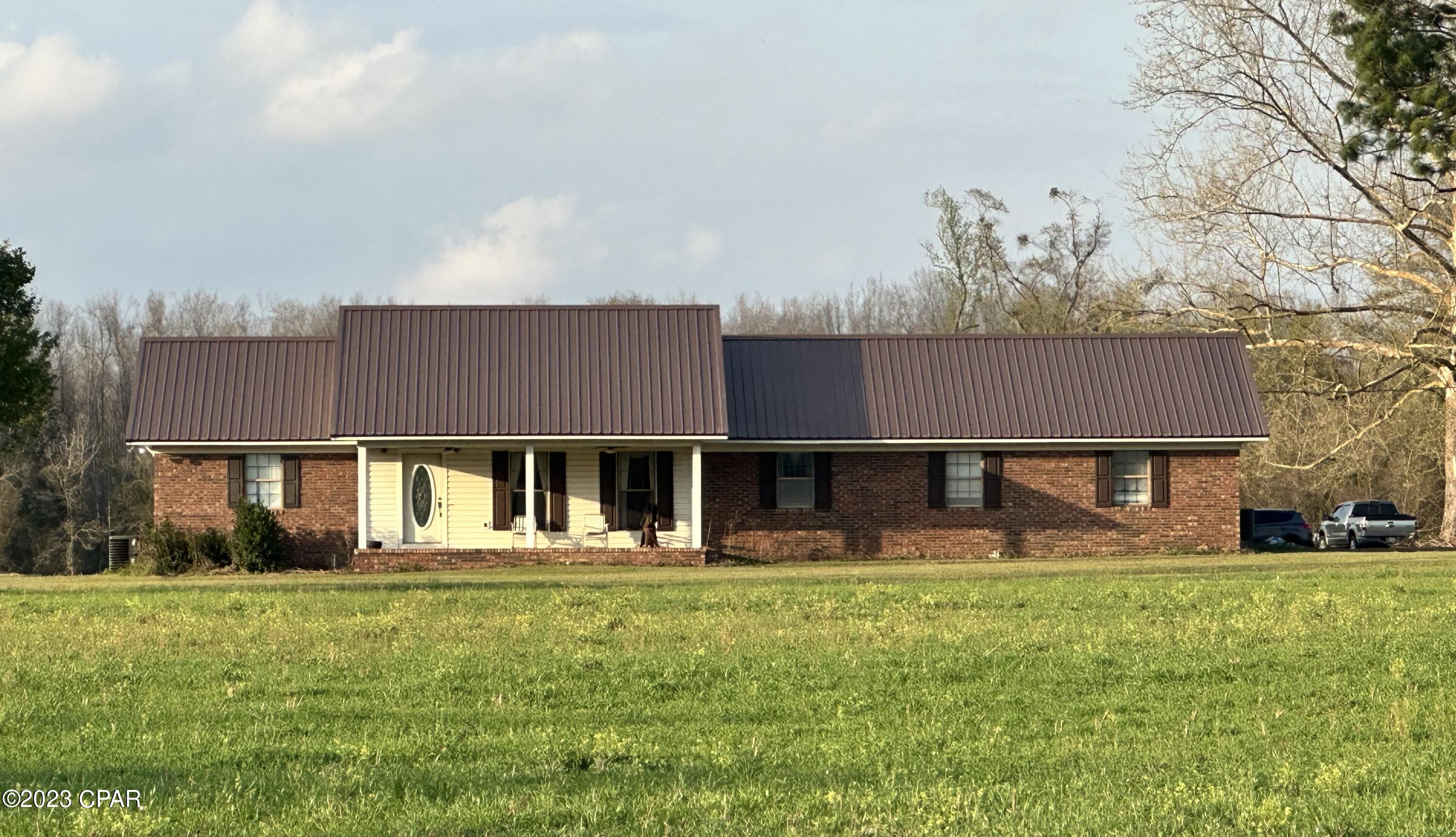 Beautiful Farm House!! 3 BR/2.5 BA with 2 offices and 61 acres with tons of Highway frontage on Highway 90, centered perfectly between Grand Ridge and Sneads!The main part of the home heated and cooled is 2,808 sq ft. With a 10x20 Heated and cooled Office at end of carport.The house has an attached 3 bay carport, a nice 12x24 screened back porch and a wood burning fireplace in the living room.There is a 1/4 mile long paved asphalt driveway to get to the house and Barndominium. The home has a new metal roof in 2019! Also, new are dual HVAC units that control each end of the home! New engineered hardwood flooring 2020! New tile flooring & tile shower in master bath!**See supplemental notes for more info on this listing***