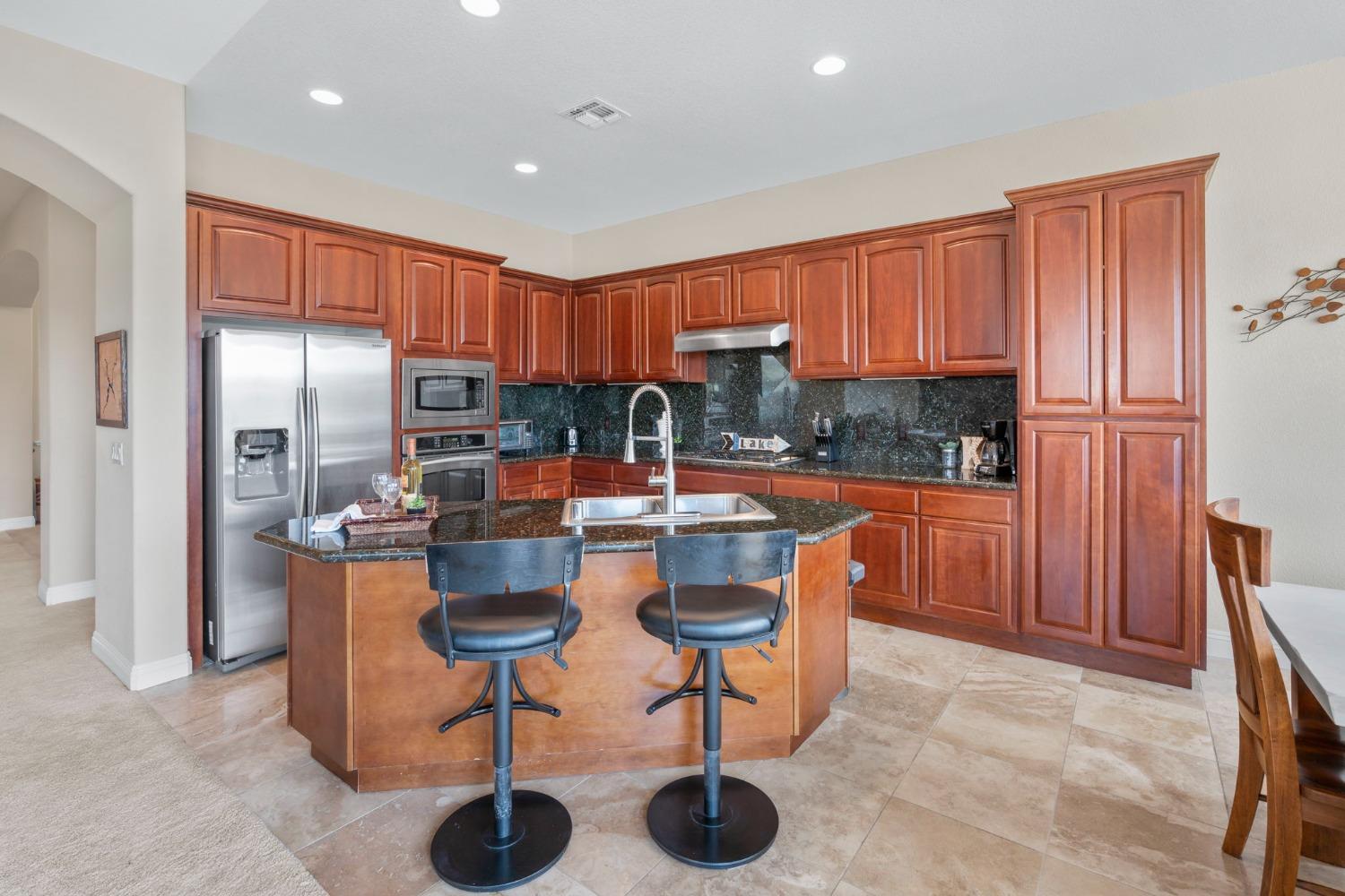 Elegant kitchen with s.s. appliances, granite slab countertops and backsplash and cherry cabinetry,