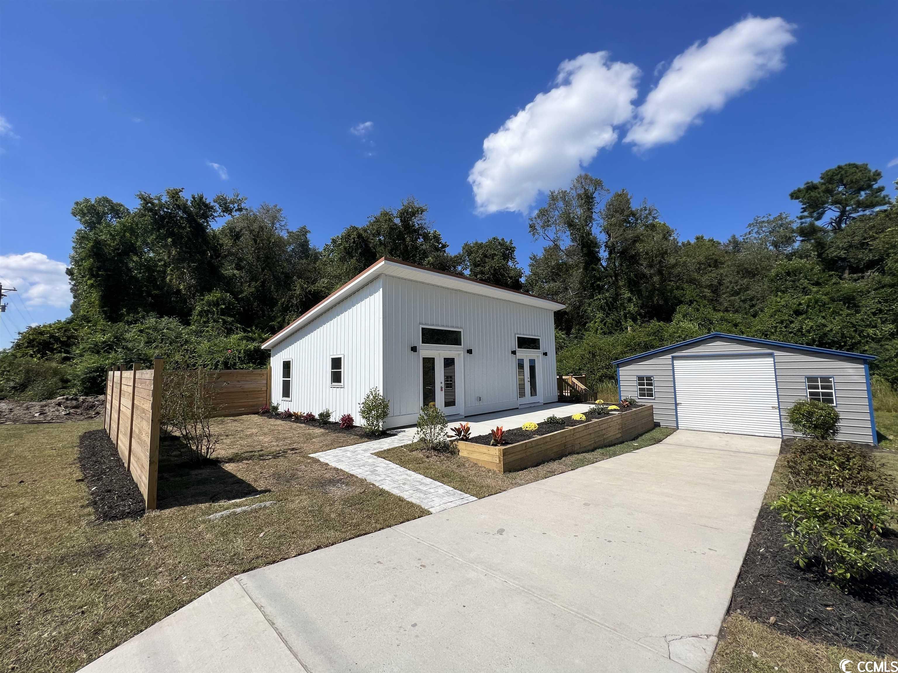 *new construction* this modern-cottage style home is move in ready! 2br/1ba with detached oversized garage/workshop measuring 24'x31' with insulated roof, 50 amp electrical service panel, 4000 psi concrete, and oversized 10'x10' door. great for rv storage etc. due to the density of the concrete. driveway leading to garage includes installed french drains. exterior of the home boasts white metal vertical siding with a stunning copper colored metal roof! 7'x31' front porch as well as a 16'x16' private back deck. modern-style privacy fence that will compliment the home's contemporary aesthetic, landscaping consist of sod, stone, mulch and a variety of plants and shrubbery. when entering, enjoy high ceilings and lots of natural light through several windows. open floor plan in the kitchen/dining/living area. all appliances included! (brand new stainless steel lg dishwasher, refrigerator, microwave, 5-burner smooth top range, and full size stackable washer & dryer). porcelain tile flooring throughout, white quartz countertops in kitchen and bathroom, sleek cabinetry with soft close drawers in white. kitchen will have 42in upper cabinets for additional storage. led lighting throughout, all hardware in matte black finish, 5 panel bedroom and bathroom doors. bathroom will offer stunning custom tile 6'x6" walk-in shower with beautiful waterfall tile accent and solid glass half wall entry. bathroom sink/cabinet has frameless anti-fog led lighted mirror. heat & air provided by 1.5 ton mini-split system and ceiling fans in each room. entire home is built with 2'x6' construction and upgraded insulation. do not miss this opportunity to own a brand new home with no hoa! located directly off hwy 90, close to coastal carolina university, downtown conway, hospitals, shopping, and minutes to the beach! schedule a tour today.