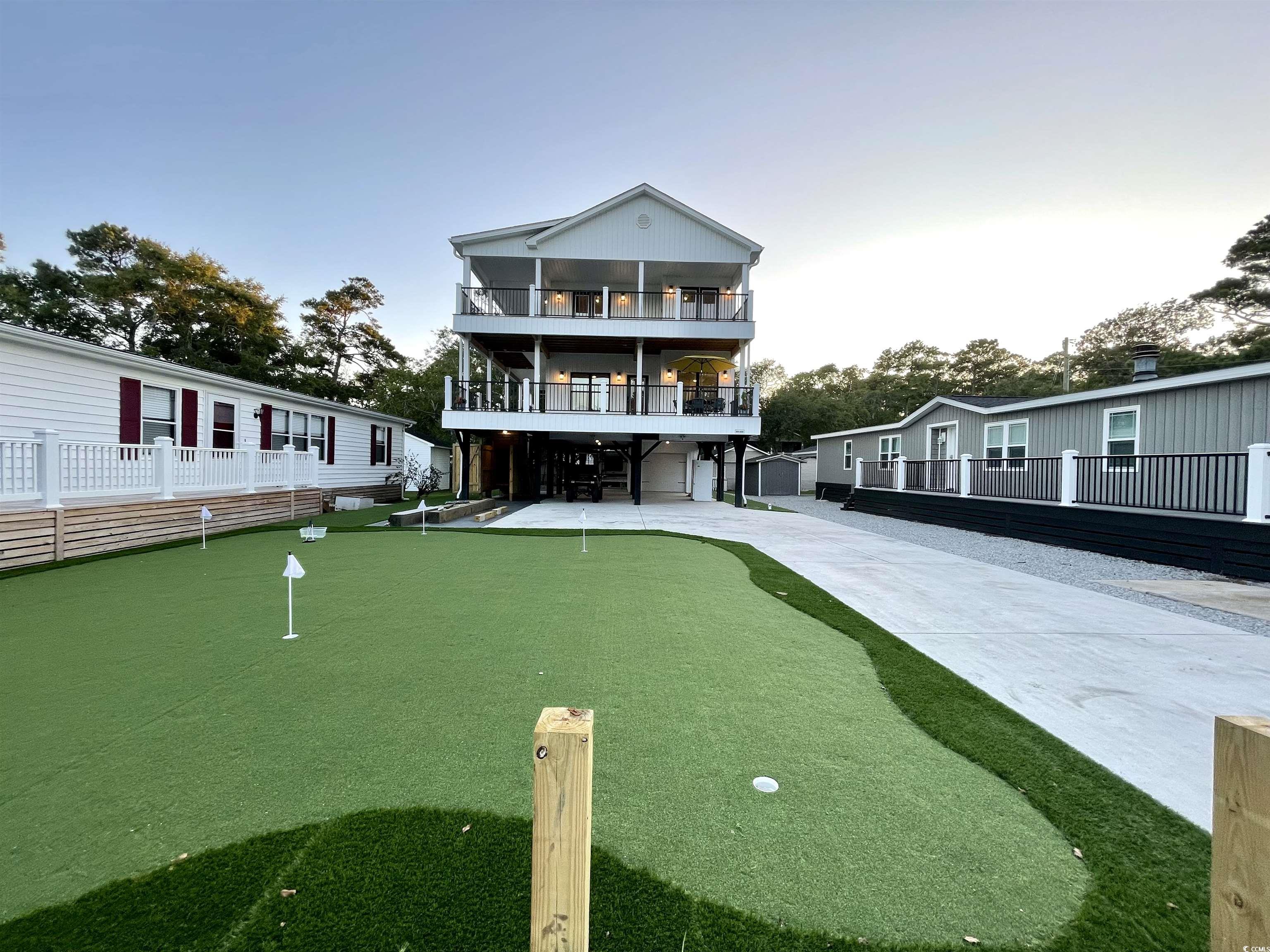 introducing "putt-ing on the beach!" this unique new construction home, completed in 2023, is virtually maintenance free and sits on an extra large double lot (by my count parking for 12). an easy walk to the beach, park and rec center. well-appointed with loads of upgrades including a private, 7 hole, putt-putt green in the front.  ditch the lawn mower because this home is surrounded by astroturf.  5 bedrooms, 4 1/2 baths with 1445 square feet of porches that were constructed with trex composite decking, another low maintenance feature (double front and side covered porches). walk through the front door and fall in love with the attention detail. bright furnishing and decor, hand chosen to bring the beach indoors. the gourmet kitchen features staggered white cabinets with crown molding, solid surface counter tops, a large center island with seating for 4 and samsung appliances. the owner's suite is located on the first floor and boasts a beautiful walk-in shower, dual vanities and built in cabinets for extra storage. walk upstairs and you will find 2 bedrooms to the rear of the home each with vaulted ceilings and share the hall bathroom. to the front of the upstairs, you will find 2 master suites each with its own private bathroom, vaulted ceilings and french doors that lead out to the massive upper deck with views for days. luxury vinyl plank flooring though-out, which is not just aesthetically pleasing but also durable and waterproof.  a 2002 club car with new batteries will convey with home. ocean lakes family campground has top-of-the-line amenities, include both an indoor and outdoor pool, lazy river, dump zone for your toddlers, arcade, mini golf, dog park, and private access to the beach.  voted best family campground year after year and winning numerous trip adviser awards and still family owned. ocean lakes has a full summer schedule for all ages and a full winter schedule to meet all your retirement dreams as well. come and take a look today. welcome home!