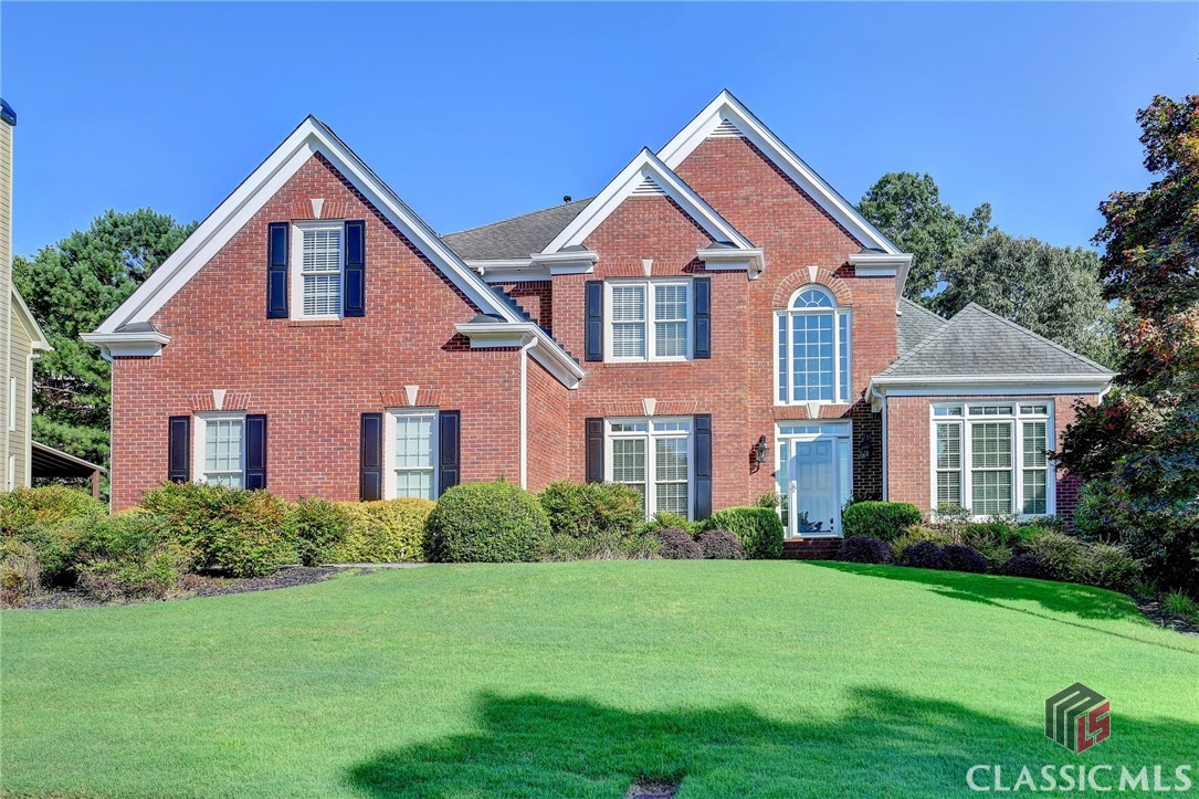Well-maintained, multi-sided brick home in the fantastic and highly desirable Hamilton Mill community and Mill Creek school district! Side entry 3-car garage upon first glance of the exterior. Step foot into the two-story foyer and you will be greeted by hardwoods throughout most of the main level, along with a formal dining room with wainscoting and ceiling medallion detail and a sitting room or office space. Soaring ceilings in the open and airy two-story great room with beautiful, large, arched windows over the fireplace with herringbone accent detail. Bright, light, gorgeously updated kitchen with newer gas cooktop, plenty of countertop and cabinet space, spacious walk-in pantry and functional laundry room off of the kitchen, enjoy breakfast with a great view through the multiple windows in the eat-in area, which overlooks the wooded and Zoysia backyard and composite deck. Enjoy your privacy with the main level primary suite, plus a half bathroom for guests. Head upstairs using the double staircase to any of the nicely sized bedrooms - one of which has its own en suite, the other two share a Jack and Jill bathroom. Finished basement that doubles as an additional living space/apartment/almost full in-law suite/kitchenette or great media/entertainment space and wet bar, plus a full bathroom! Potential for a craft/hobby room and workshop or great storage space or additional finished spaces. This home is move-in ready and perfect for those needing separate, multiple living spaces for their families or guests! Conveniently located near tons of local conveniences, dining, Little Mulberry Park, I-85, Puckett's Mill Elementary and Mill Creek High School and more!