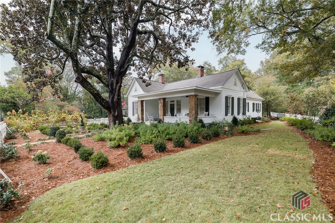 NOTE: Single level Main House has 3 BR/2.5 Baths and 2522 sq/ft and the 2-story Carriage House has 1 BR/1 BA with approx. 900 sq/ft for a total of 4 Bedrooms/3.5 Baths and approx 3422 sq/ft for this property. Beautiful and meticulous restoration in the Cloverhurst-Springdale Historical Neighborhood in Five Points.   After entering the spacious front porch for relaxing gatherings, you enter the parlor with 12’+ ceilings and fireplace.  The main house has 12’+ and 10’ ceilings.  Restoration work that began in 2017 included the creation of a dining room, breakfast area, laundry room and unique bunkbed area with the overall design to create continuity with the architecture of the historic house and neighborhood.  There is an additional living room with fireplace and high ceilings having access to the new kitchen. The kitchen features the finest in kitchen appliances with double ovens,  under counter microwave drawer, Wolf gas cooktop and KitchenAid French door refrigerator.  There is plenty of counter top space for the serious cook in the family.  The laundry room is well designed and spacious and offers some flex space if needed. There is plenty of space for a large formal dining room to seat a big group of friends or family.    The primary bedroom in the main house has custom bath with shower and boasts of the best design and fine finishes of marble flooring and walls.  The powder room also has marble flooring. The second bath is beautifully renovated.   In the center of the house is another flex room currently being used a bunk bed area.  The  entire house is light and bright. An alarm system which includes smoke and carbon monoxide detectors as well as glass breakage alarms.  The  2-level Carriage house was created. The first level functions as an indoor/outdoor space including sink, refrigerator and icemaker while the second level features a guest suite including the bedroom, bathroom and ample closet space.    The spacious patio area connecting the main house and the carriage is well designed for entertaining.   The entire property is fenced and has a remote controlled gate.   A spray and drip irrigation system is part of the extensive landscaping.   
The restoration work was completed in September of 2018 which included rewiring of older structure, roof replacement, new kitchen, replacement of the HVAC system and installation of new hardwood flooring as well as restoration of the original hardwood floors.   History abounds with this home which originally belonged to Judge Hamilton McWhorter and later owned by Robert L. McWhorter who was UGA first All American football player who went on to become a professor of law at UGA and mayor of Athens.