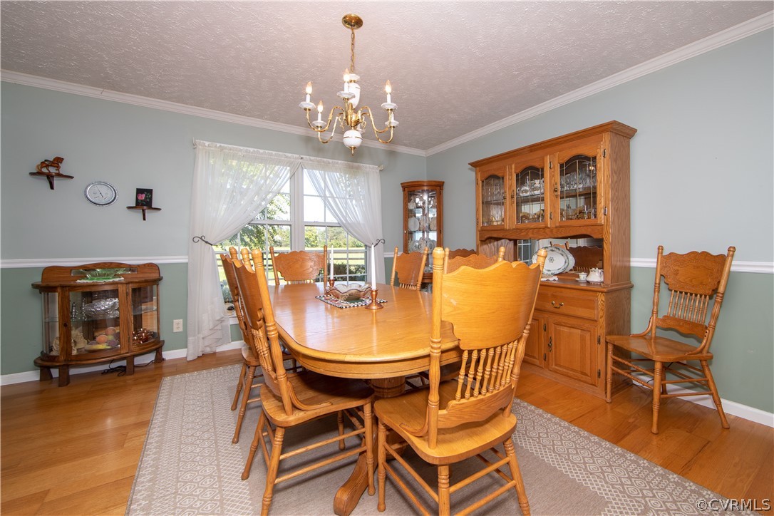 The beautiful and sophisticated dining room offers wood floors, chair rails, a chandelier and lots of natural light.