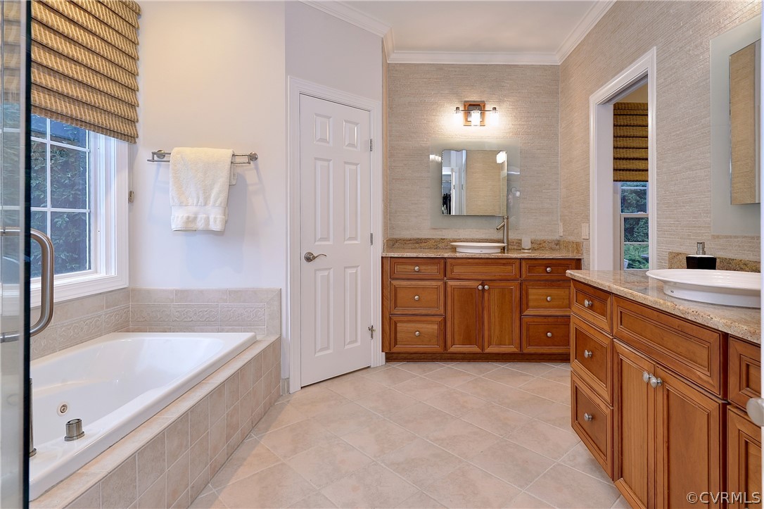The primary suite bath features a tiled floor, two vanities, jetted tub and step-in shower.
