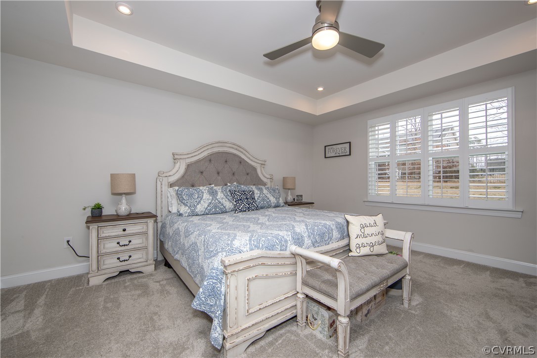 Large 1st level primary bedroom with tray ceiling with recessed lighting, plantation shutters