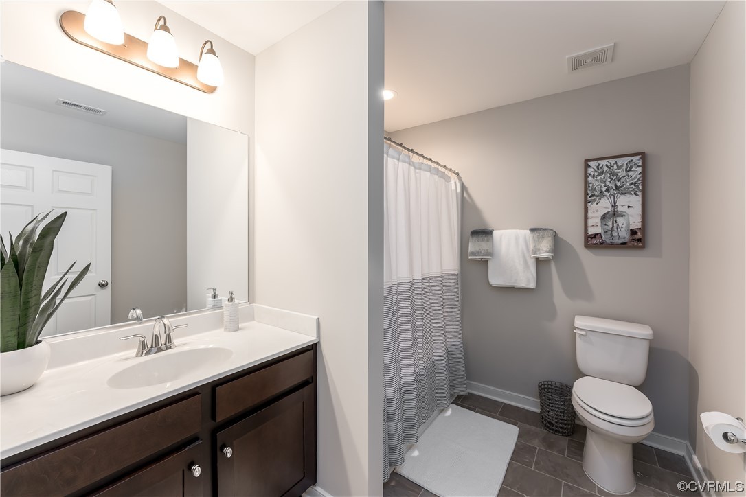 Bathroom with vanity with extensive cabinet space, toilet, and tile floors