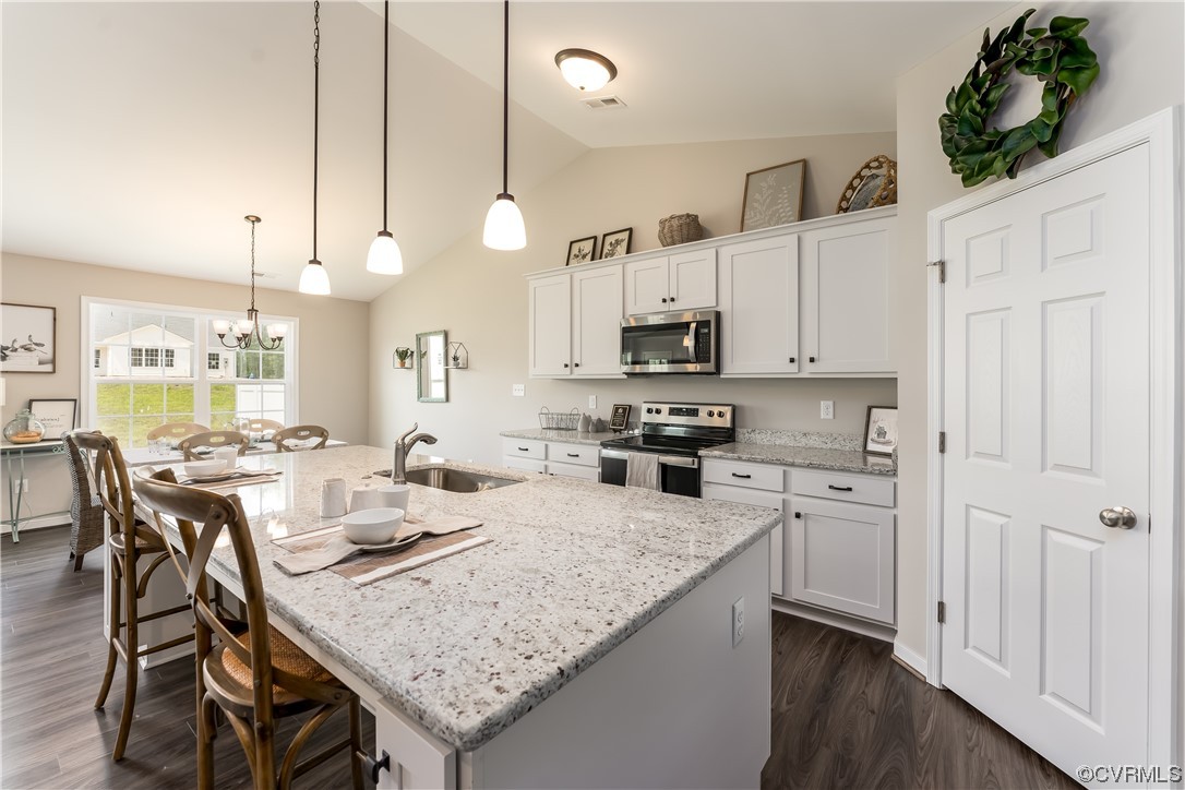 Kitchen featuring stainless steel appliances, white cabinets, and an island with sink
