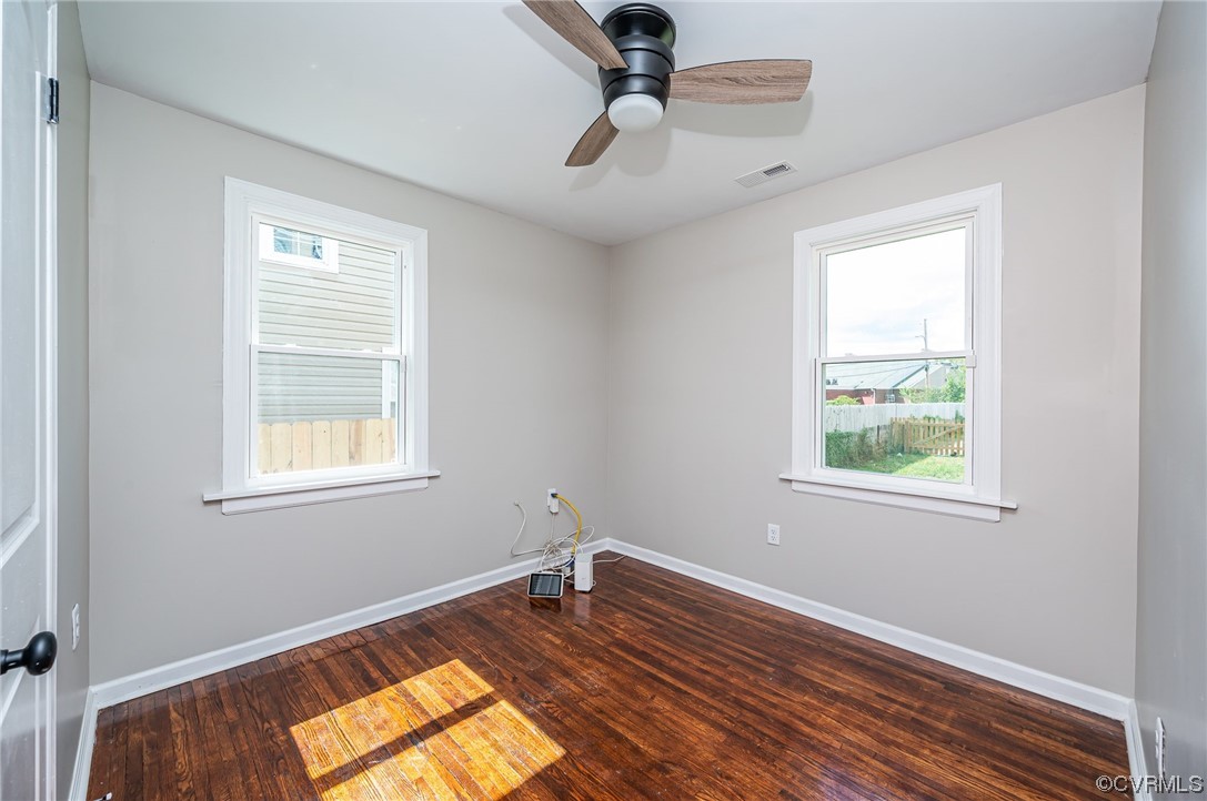 Wood floored spare room with natural light and a ceiling fan