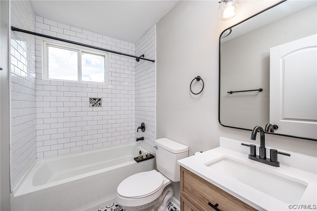 Full bathroom with toilet, bathtub / shower combination, mirror, and vanity with extensive cabinet space