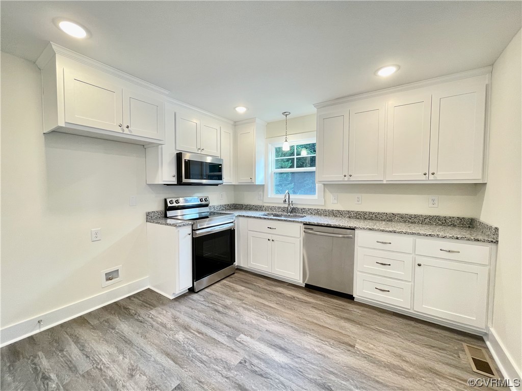 Kitchen with natural light, electric range oven, microwave, dishwasher, white cabinets, light countertops, and LVP floors