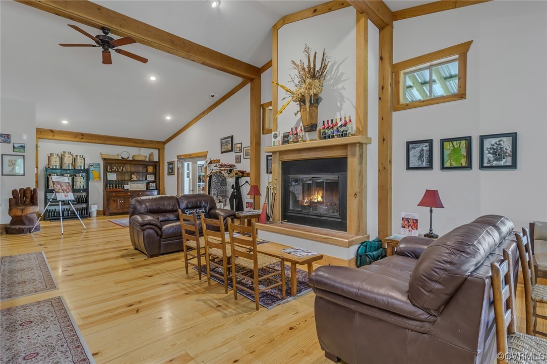 Hardwood floored living room with a fireplace, a ceiling fan, and wood beam ceiling