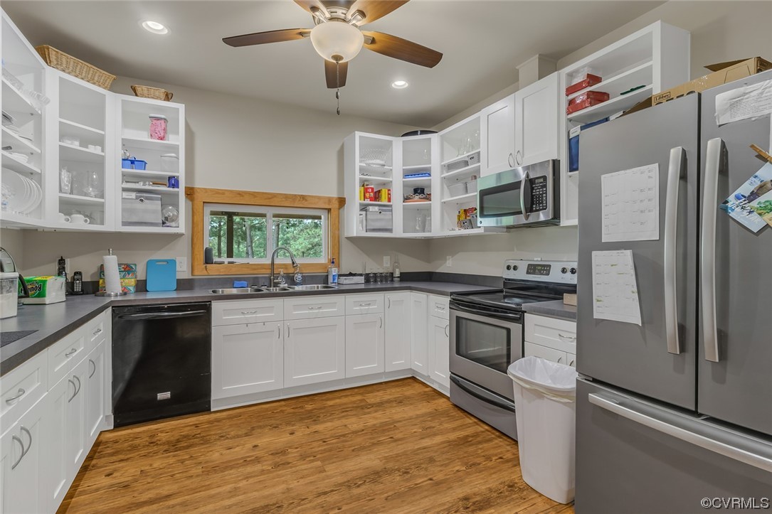 Kitchen featuring a ceiling fan, natural light, dishwasher, refrigerator, microwave, electric range oven, light hardwood flooring, white cabinets, and dark countertops