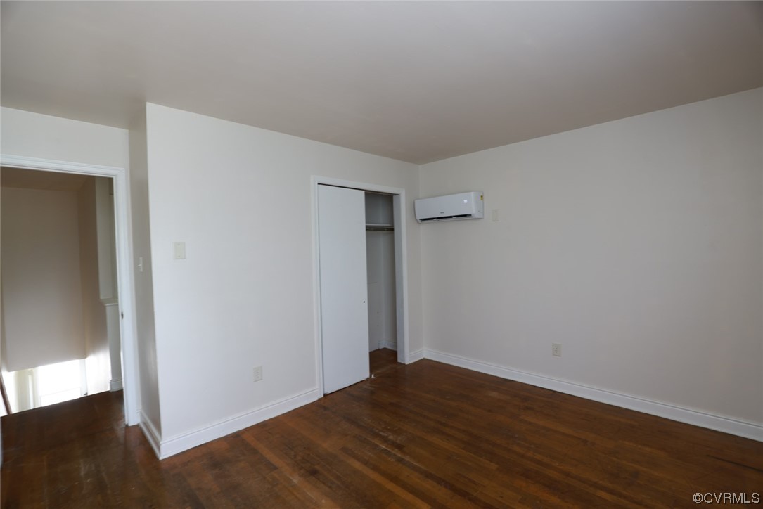 Hardwood floored bedroom with a wall mounted air conditioner