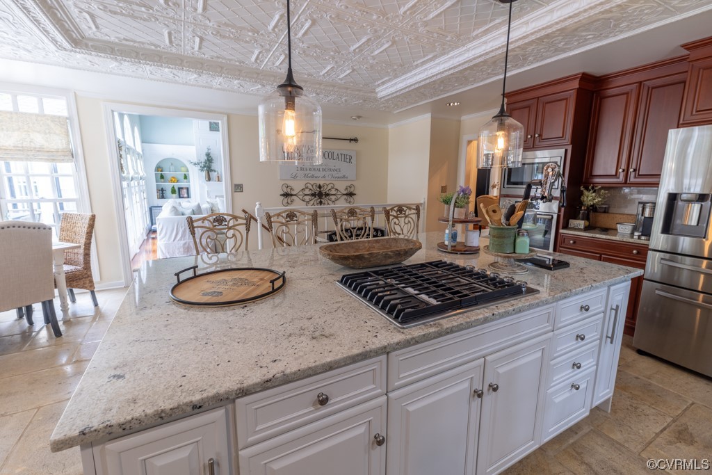 Kitchen featuring tile floors, gas stovetop, refrigerator, light stone countertops, and pendant lighting