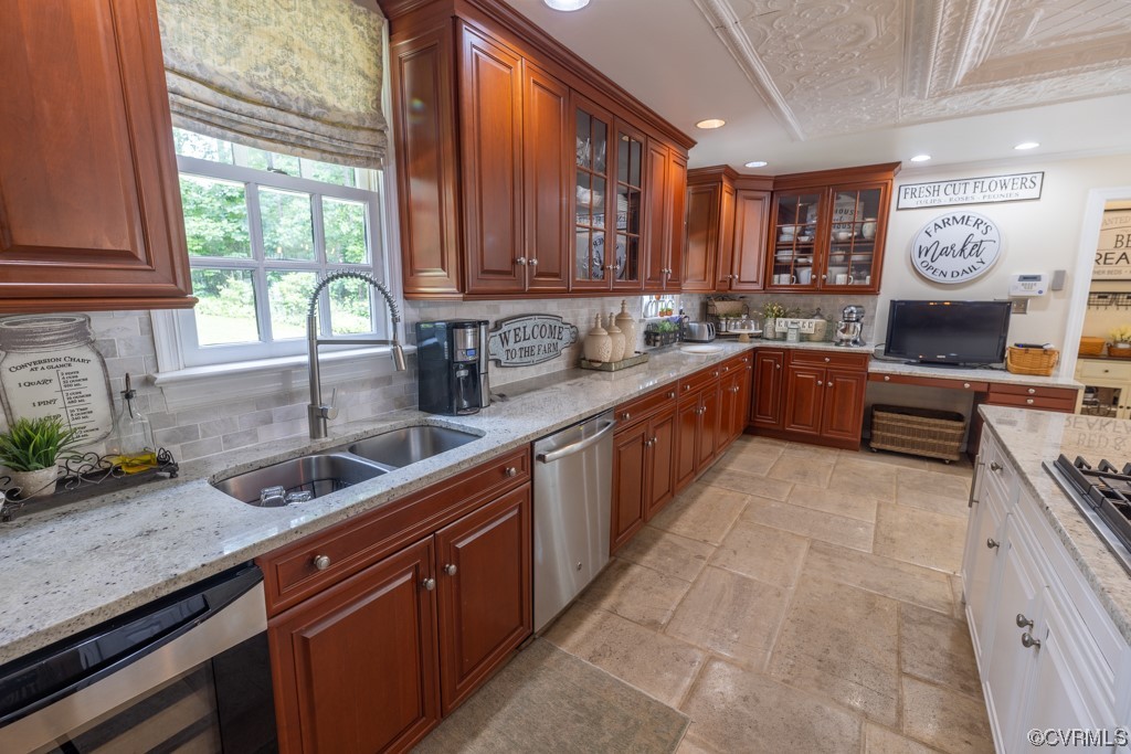 Kitchen featuring a wealth of natural light, stainless steel dishwasher, TV, light tile flooring, and light stone countertops