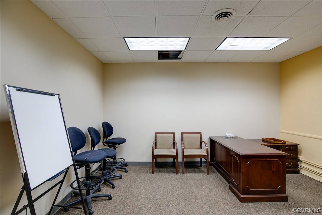 Carpeted office space with a baseboard heating unit and a drop ceiling