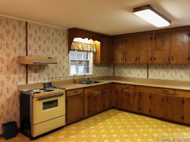 Kitchen featuring light tile flooring, fume extractor, light countertops, brown cabinets, ornamental molding, and electric range oven