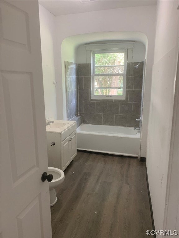 Full bathroom featuring dark hardwood flooring, tiled shower / bath, and vanity