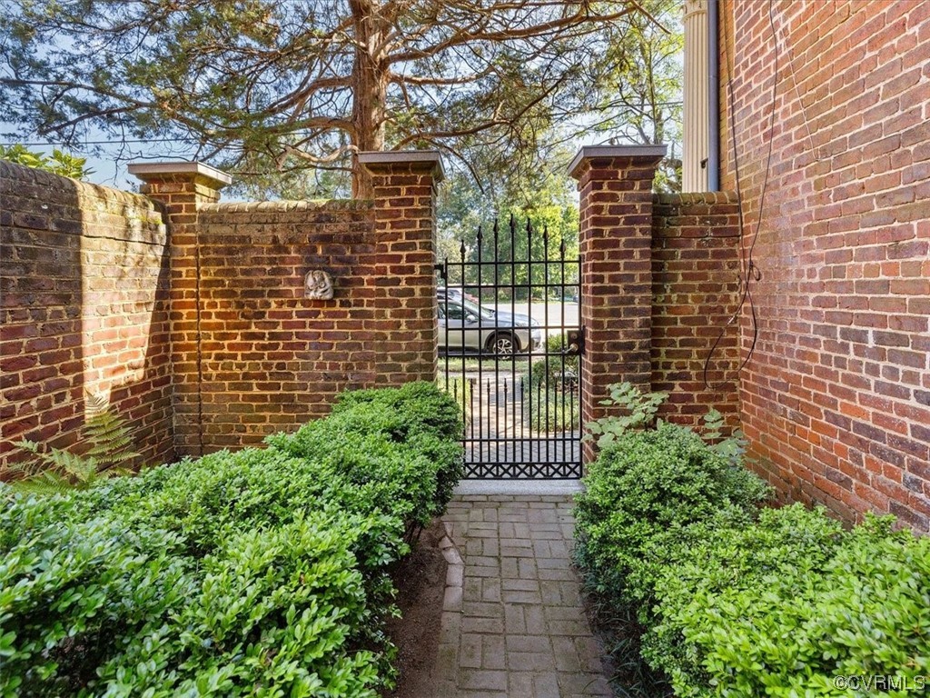 A substantial brick wall and iron gate reinforce the privacy.