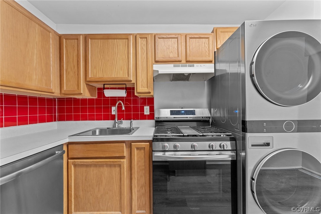 Kitchen with sink, tasteful backsplash, stacked washer / drying machine, and appliances with stainless steel finishes