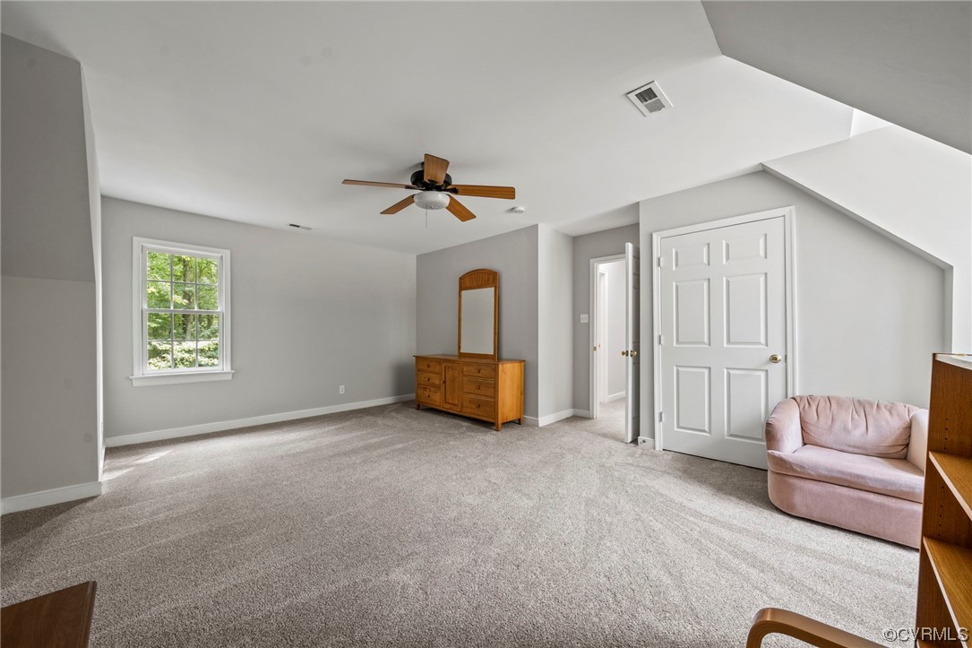 Living area featuring light carpet and ceiling fan