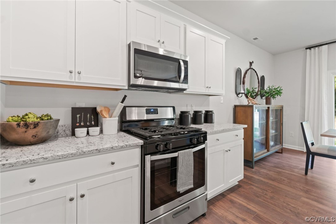 Kitchen with stainless steel appliances, light countertops, hardwood flooring, and white cabinets