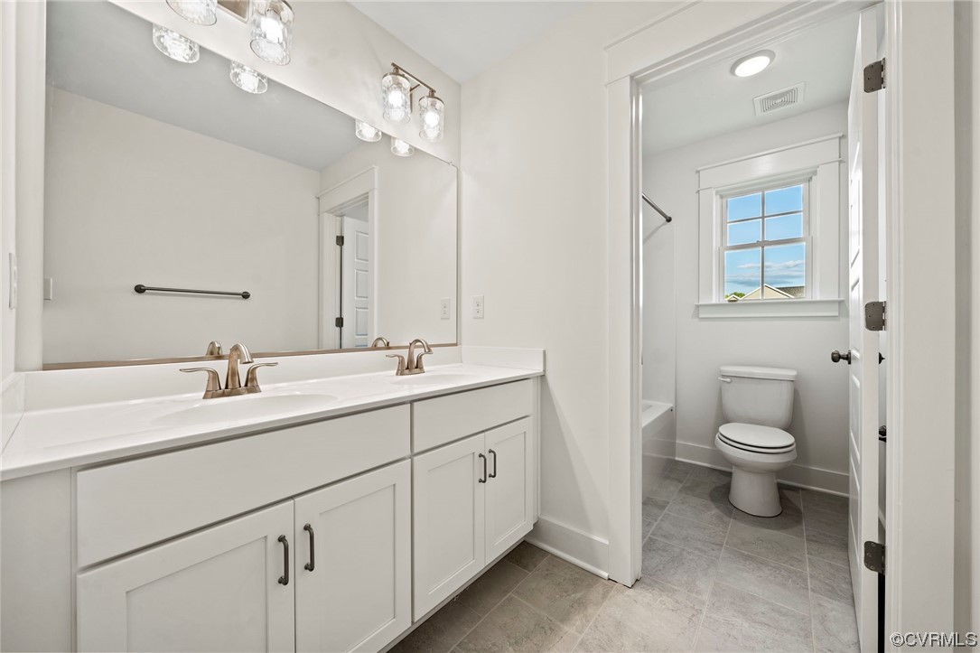 Full bathroom with  shower combination, double vanity, mirror, and light tile flooring