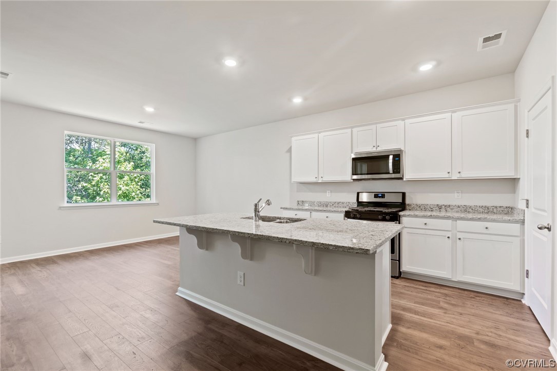Kitchen featuring light hardwood floors, sink, white cabinetry, and appliances with stainless steel finishes