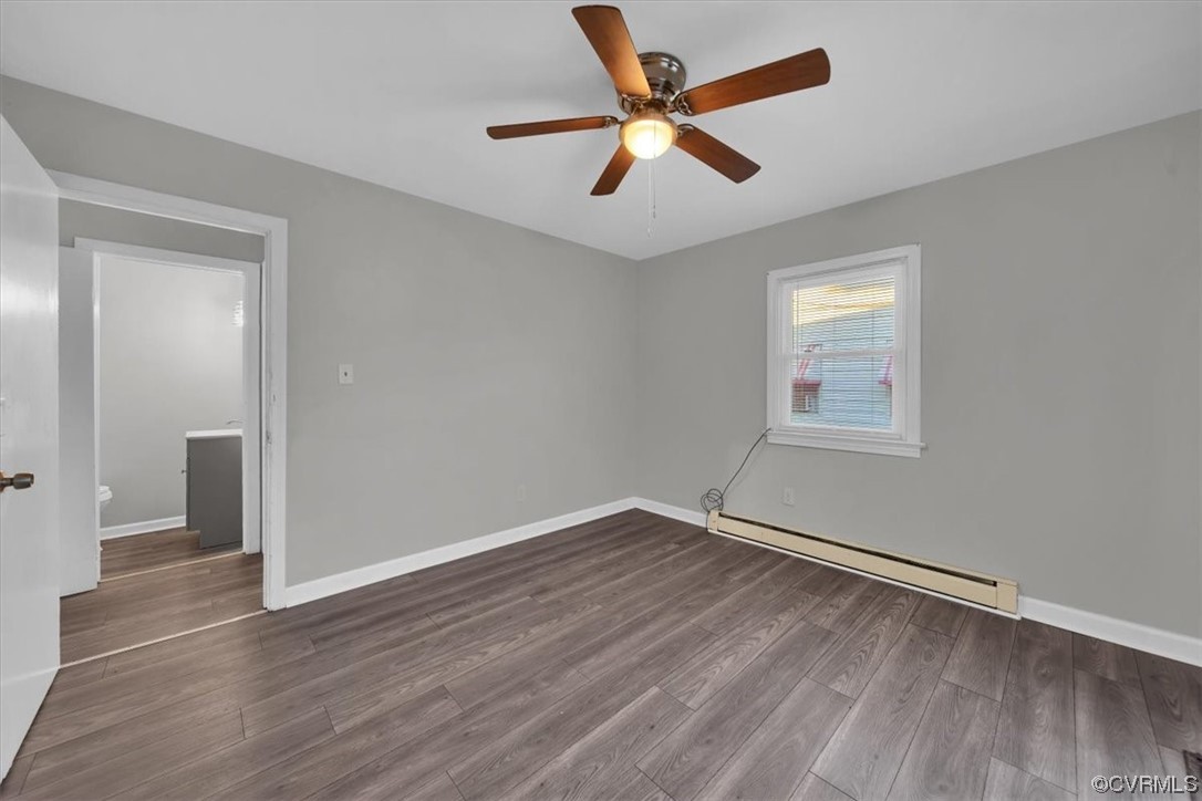 Hardwood floored spare room with a baseboard radiator and ceiling fan