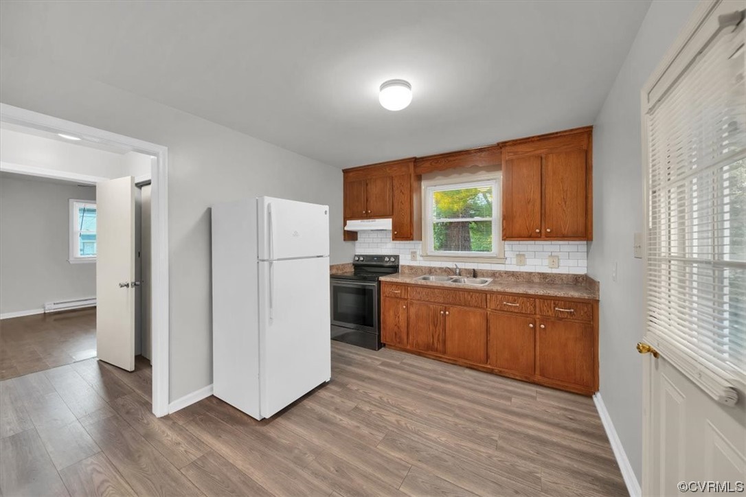 Kitchen with tasteful backsplash, electric stove, light hardwood floors, a baseboard radiator, and white refrigerator