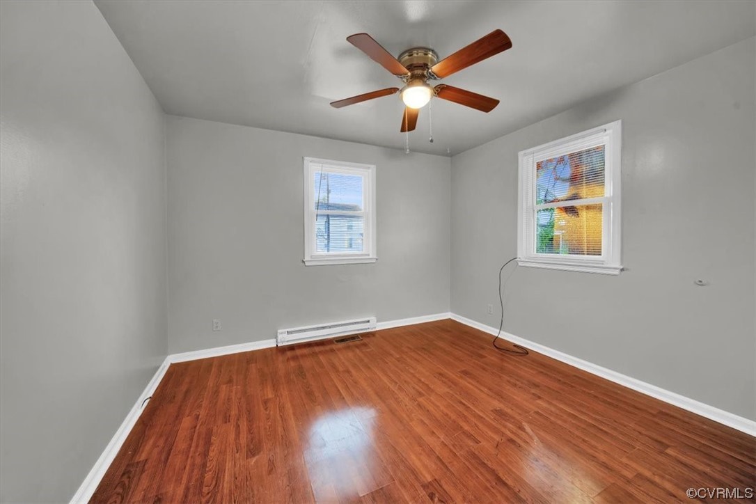 Spare room with wood-type flooring, a wealth of natural light, and ceiling fan