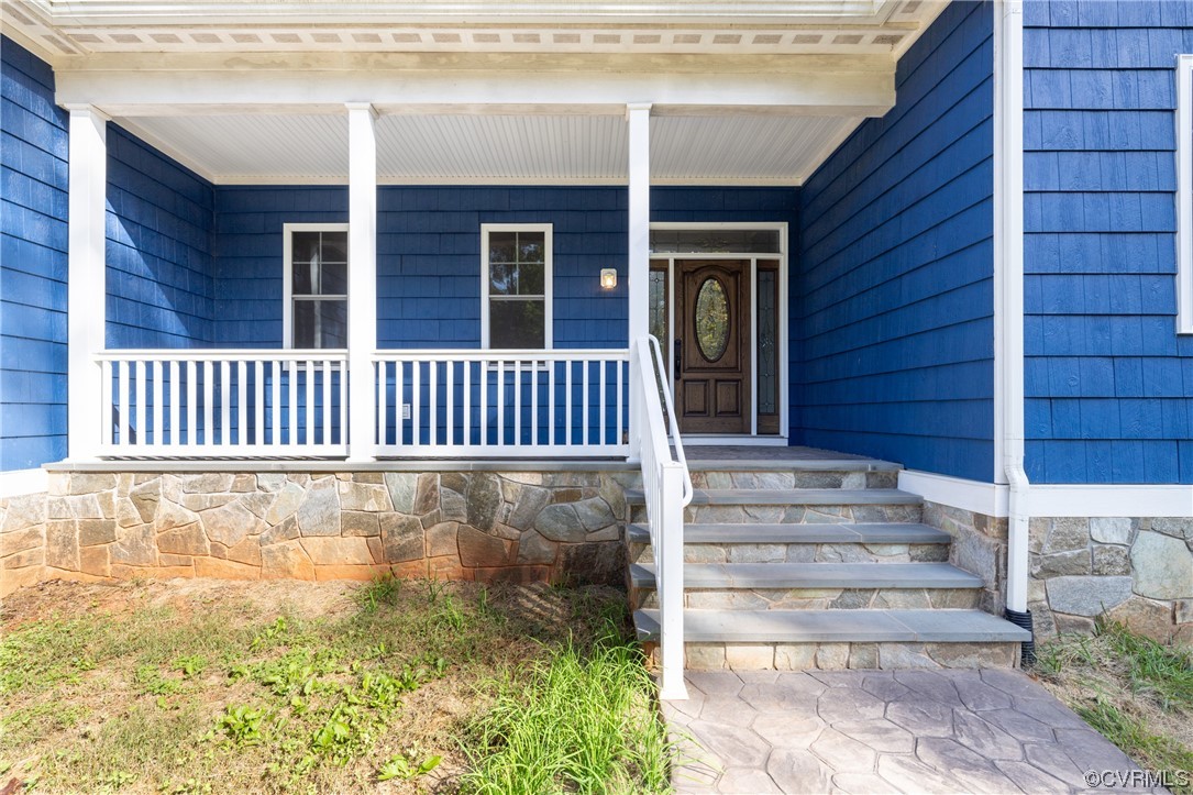 Front door to property featuring covered porch
