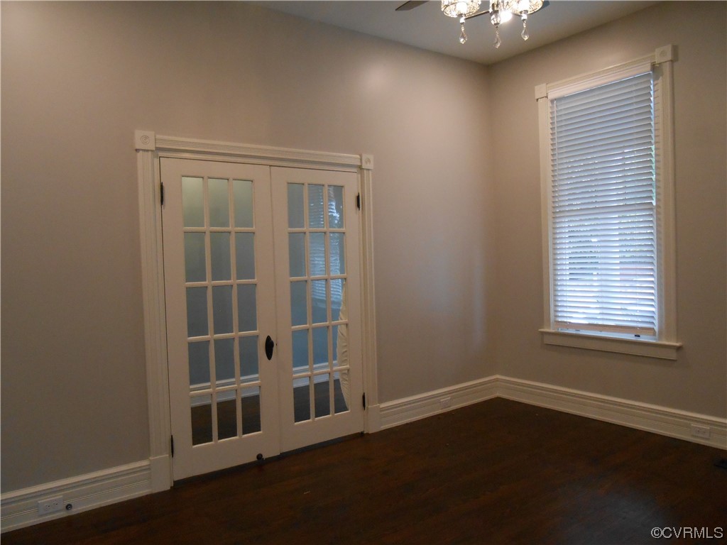 Wood floored spare room with french doors and ceiling fan with notable chandelier