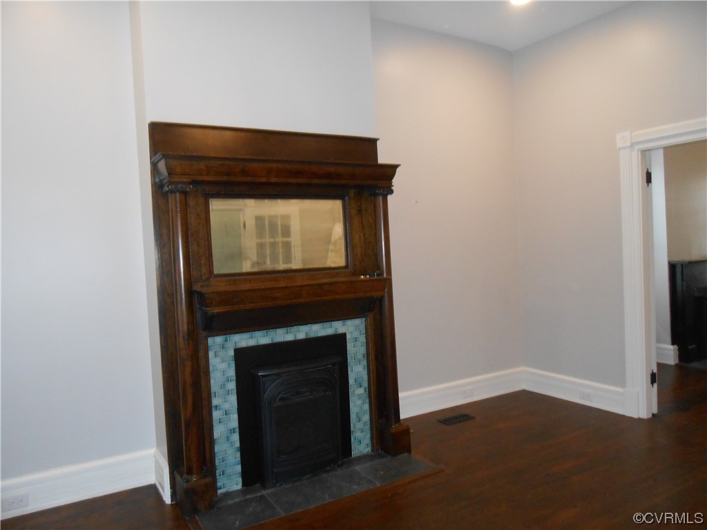 Unfurnished living room with a fireplace and dark hardwood flooring
