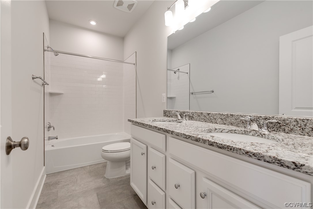 Full bathroom with tile flooring, toilet, tiled shower / bath, and dual bowl vanity
