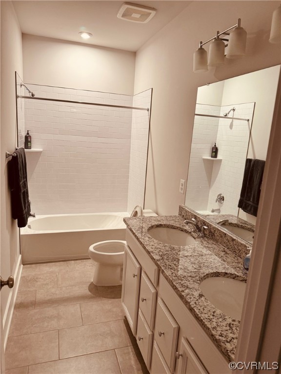 Full bathroom with tiled shower / bath combo, toilet, tile floors, and dual bowl vanity