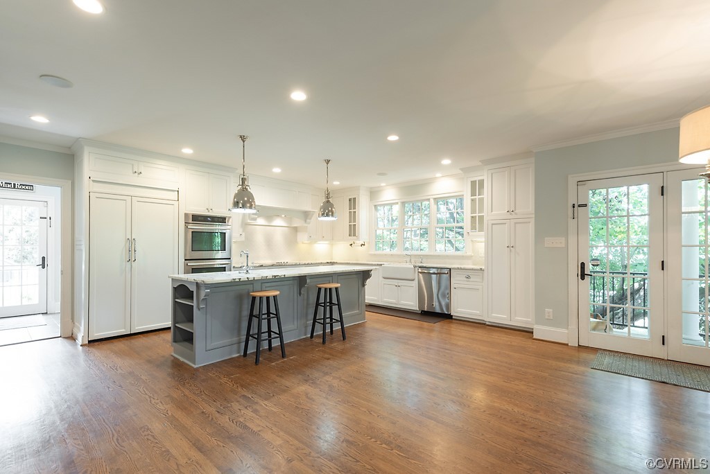 Kitchen with white cabinetry, a kitchen island with sink, and dark hardwood floors