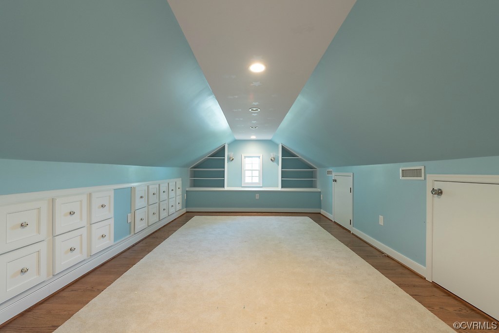 Additional living space with hardwood flooring and lofted ceiling