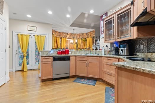 Kitchen featuring a chandelier, stainless steel dishwasher, light hardwood / wood-style floors, pendant lighting, and fume extractor
