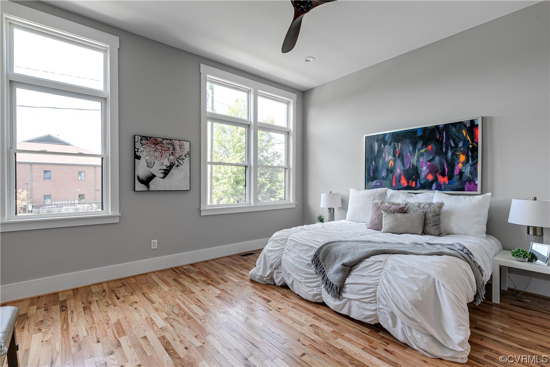 Bedroom with multiple windows, light hardwood floors, and ceiling fan