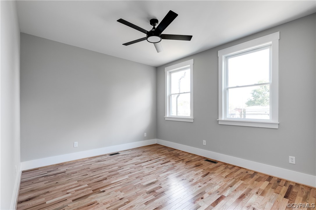 Wood floored empty room featuring ceiling fan