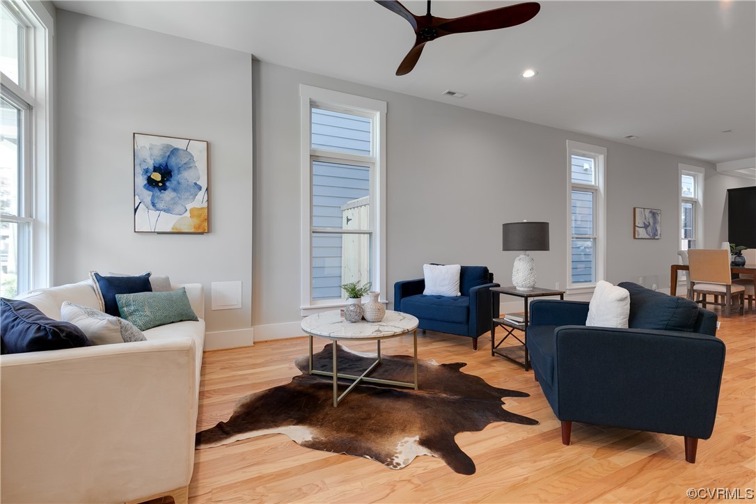 Hardwood floored living room featuring a healthy amount of sunlight and ceiling fan