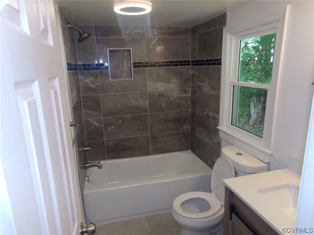 Full bathroom featuring tiled shower / bath, vanity, and toilet