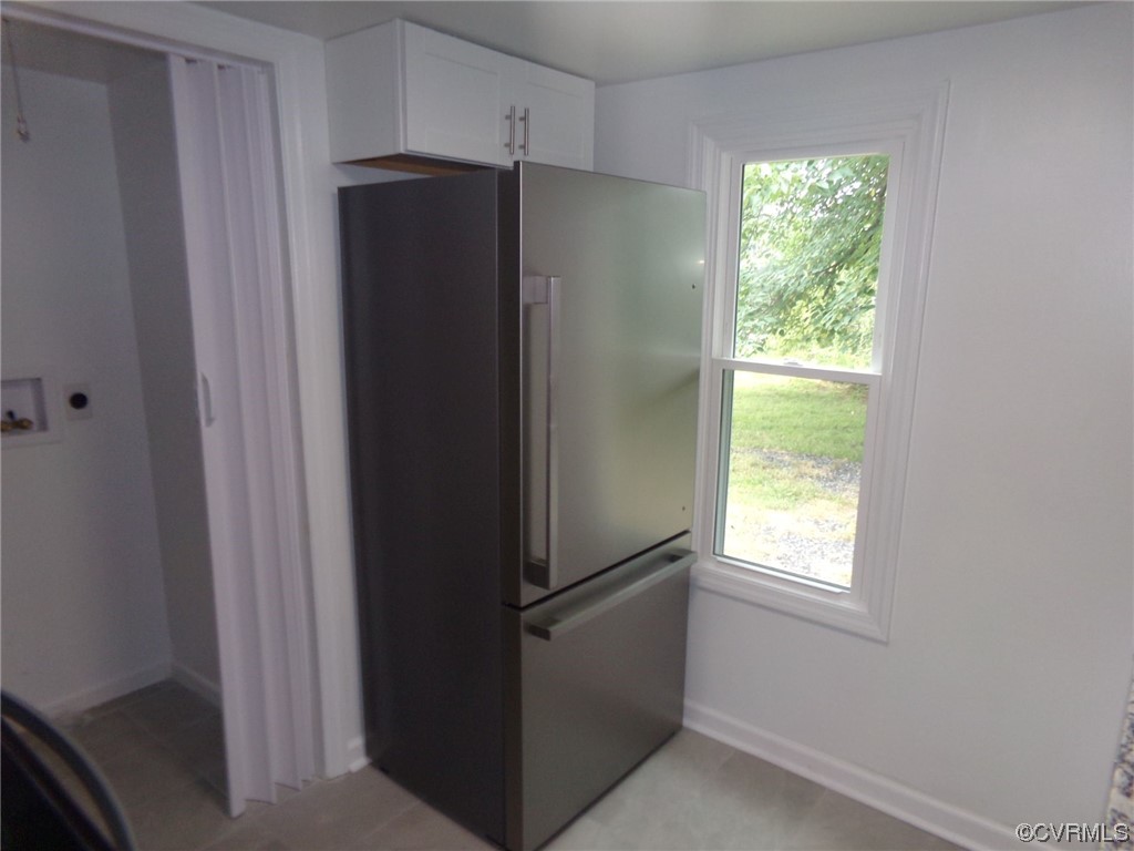 Kitchen featuring white cabinets and stainless steel refrigerator