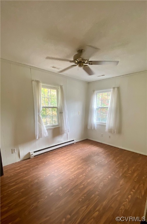 Empty room featuring plenty of natural light, wood-type flooring, ceiling fan, and a baseboard radiator