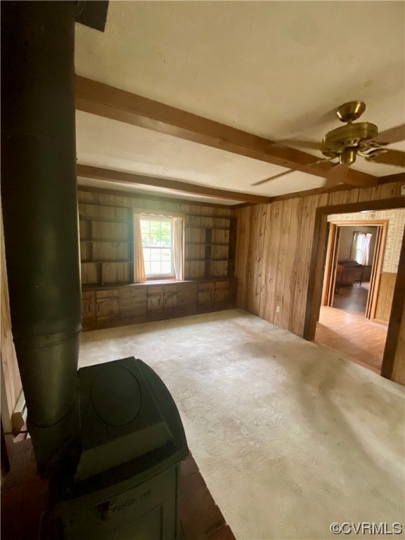 Spare room featuring beamed ceiling, ceiling fan, and wooden walls