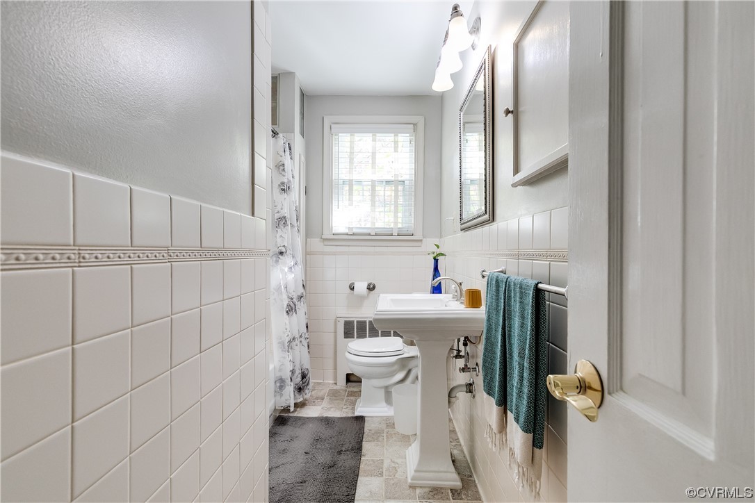 Bathroom featuring tile flooring, sink, toilet, and tile walls