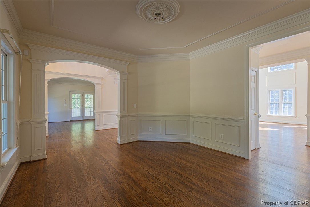 Formal dining room with dark wood-type flooring, great sunlight, crown molding, and ornate columns flows into the kitchen and family room